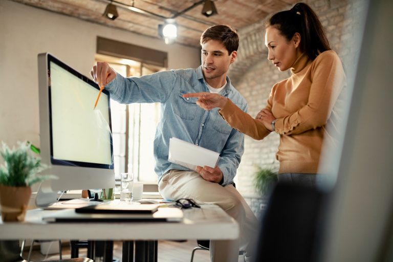 Two coworkers cooperating while using computer and working in the office.